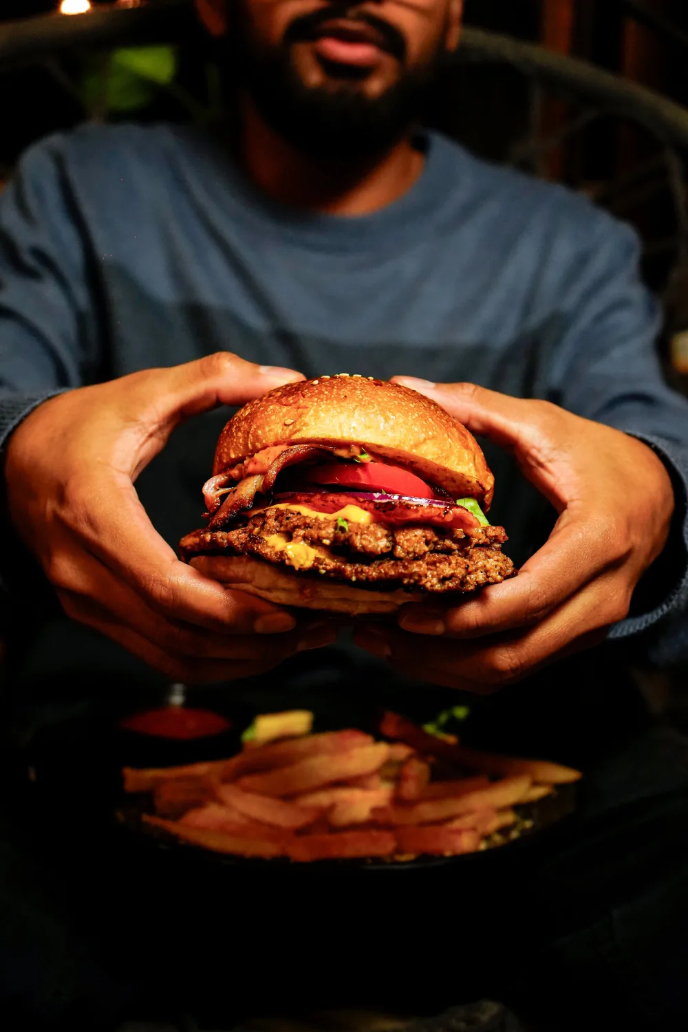 Hamburguesa recién servida entre las manos de un comensal